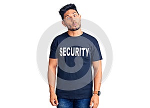 Handsome latin american young man wearing security t shirt making fish face with lips, crazy and comical gesture