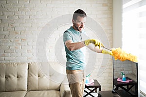 Handsome Latin man dusting his house