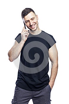A handsome laughing man in a black t-shirt is talking on the phone. Career, business and success. Isolated on white background.