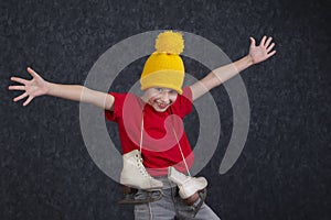 Handsome little boy in a knitted yellow hat with vintage skates