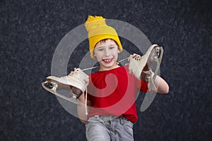 Handsome little boy in a knitted yellow hat with vintage skates