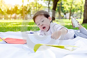 Handsome little boy is opening a book for reading and learning by himself at a park. Charming handsome kid love reading and lookin