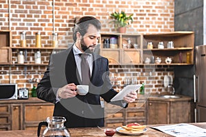 handsome loner businessman holding tablet and cup of coffee