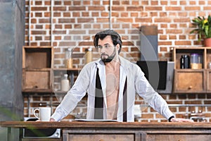 handsome loner businessman standing in unbuttoned shirt