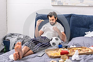 handsome loner eating pizza on bed