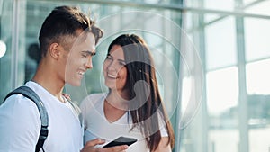 Handsome Lovely Couple standing near the Airport or Railway Station. They Pointing with her Finger in the Smartphone