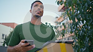 Handsome mailman delivering package greenery neighbourhood closeup. Mail courier