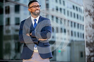 Handsome male african american business man CEO in a suit at the workplace, standing confidently with arms folded