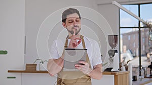 Handsome male bartender in a restaurant cafe making online order on a tablet.