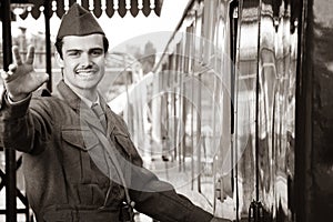 Handsome male British soldier in WW2 vintage uniform at train station next to train