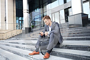 Handsome male business executive sitting on stairs outside a building.