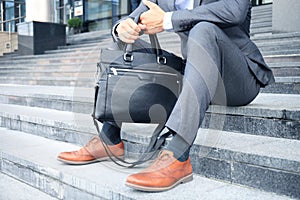 Handsome male business executive sitting on stairs outside a building.