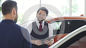 Handsome male car dealer talking to his male customer