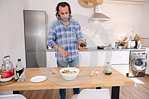 Handsome male chef cooking salad in the minimalist home kitchen
