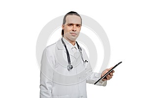 A handsome male doctor holds a tablet in his hands and looks at the camera.