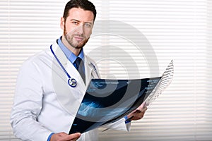 Handsome male doctor portrait holding patients x-ray