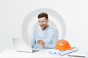 Handsome male engineer is using a notebook for work. He is sitting at the desk and smiling. Copy space on side.