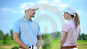 Handsome male golfer smiling to female partner before competition, flirt