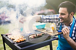 Handsome male grilling meat outdoor