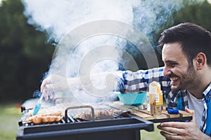 Handsome male grilling meat outdoor