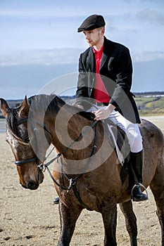 Handsome Male Horse Rider riding horse on beach in traditional clothing