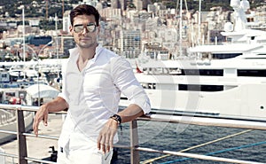 Handsome male model posing in front of a luxury yacht