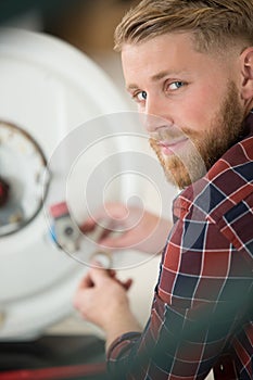 Handsome male plumber working with boiler