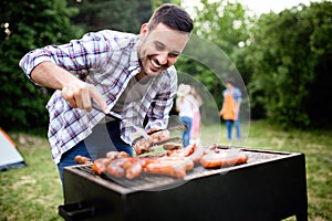 Handsome male preparing barbecue, grill outdoors for friends