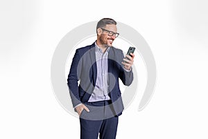 Handsome male professional manager with hand in pocket messaging online on mobile phone. Elegant businessman reading e-mails on