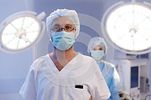 A handsome male surgeon with glasses is in a medical hospital room with a nurse standing behind him in very good