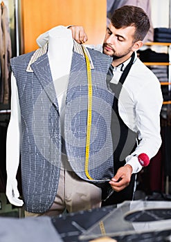 Handsome male tailor working in atelier