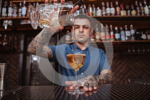 Handsome male tattooed bartender preparing a drink