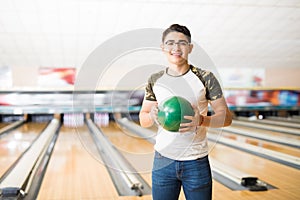 Teenager With Green Bowling Ball At Alley