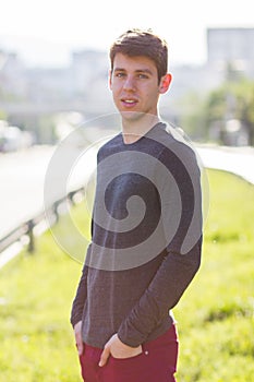 Handsome male teenager in grey shirt outdoors