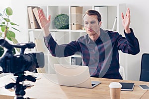 Handsome male video blogger in violet shirt recording vlog and gesturing