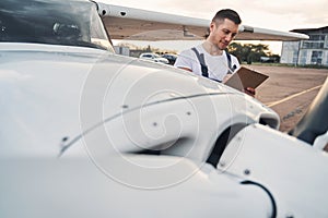 Handsome male worker writing on clipboard at airdrome