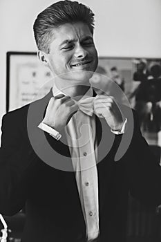 Handsome man adjusts his bow tie smiling