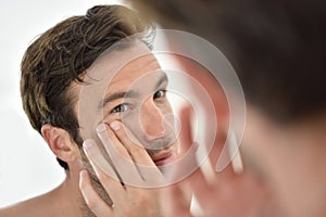 Handsome man applying facial cream photo