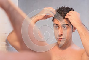 Handsome man applying hair gel