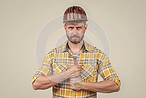 handsome man assistant in construction safety helmet and checkered shirt on building site with hammer, improvement