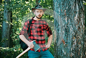 Handsome man with axe. Stylish young man posing like lumberjack. Deforestation is a major cause of land degradation and