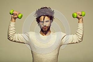 Handsome man with barbell doing morning exercise, has uncombed hair