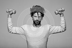 Handsome man with barbell doing morning exercise, has uncombed hair