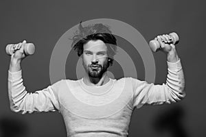 Handsome man with barbell doing morning exercise, has uncombed hair