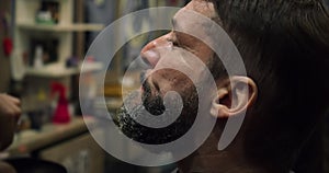 Handsome man in a barbershop shaves his beard in a hair studio. A professional hairdresser paints a client man beard