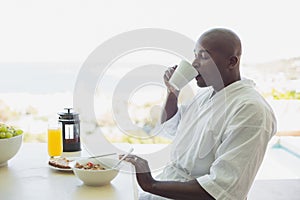 Handsome man in bathrobe having breakfast outside