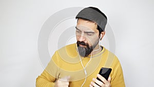 Handsome man with beard listening to music with headphones on smartphone
