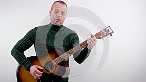 handsome man with a beard plays beautiful melody on an acoustic guitar. White background. Isolated. Medium long shot