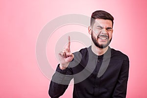 Handsome man with beard pointing in one direction on a blue background