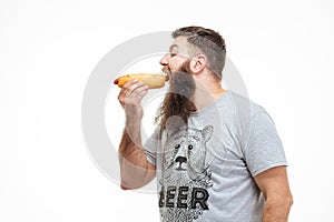 Handsome man with beard standing and eating hot dog photo